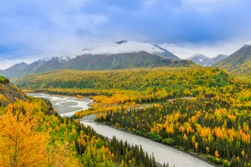 Autumn forest, braided river, and cloud-covered mountains in Alaska